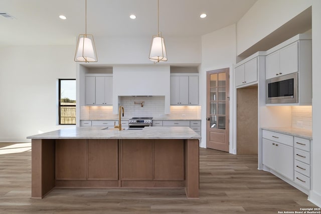 kitchen featuring stainless steel appliances, a sink, visible vents, light wood-style floors, and tasteful backsplash