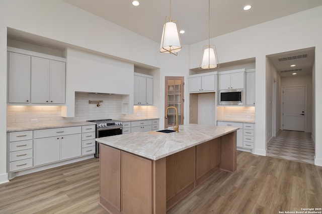 kitchen with visible vents, light wood-style floors, white cabinetry, a sink, and recessed lighting