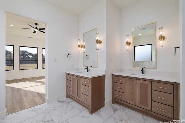 bathroom with marble finish floor, two vanities, a sink, and baseboards