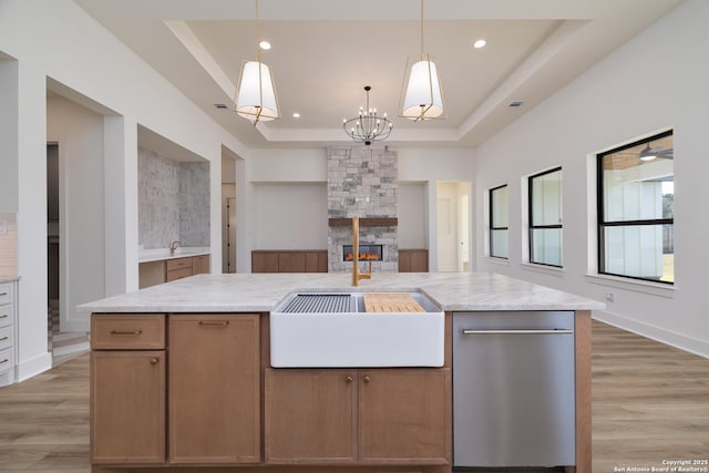 kitchen with recessed lighting, light wood-style flooring, a tray ceiling, and a stone fireplace