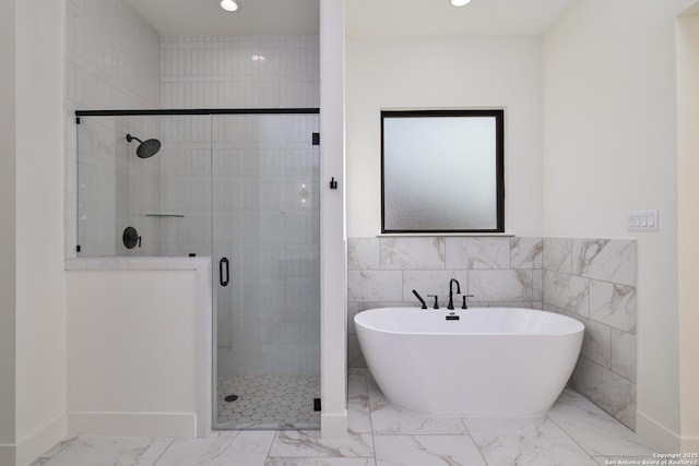 full bathroom with marble finish floor, a freestanding tub, a shower stall, and recessed lighting