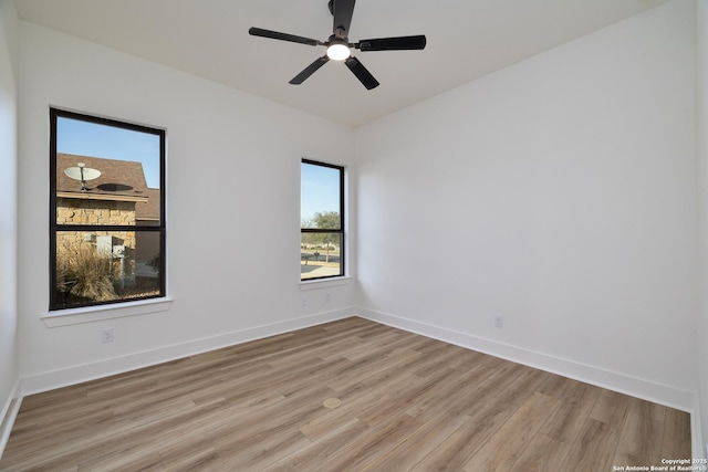 spare room featuring light wood-type flooring, baseboards, and a ceiling fan