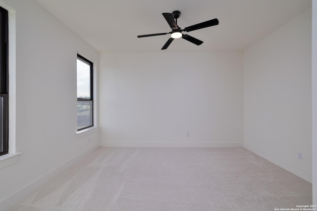 empty room featuring baseboards, a ceiling fan, and light colored carpet