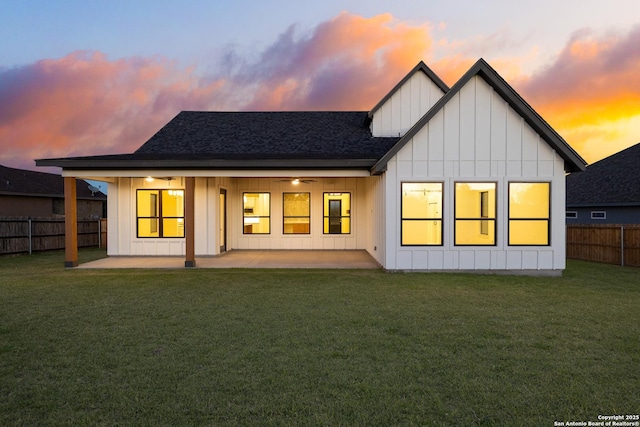 back of house featuring ceiling fan, a yard, board and batten siding, and a fenced backyard