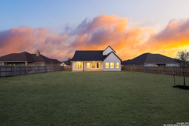 back of house with a fenced backyard, a lawn, and board and batten siding