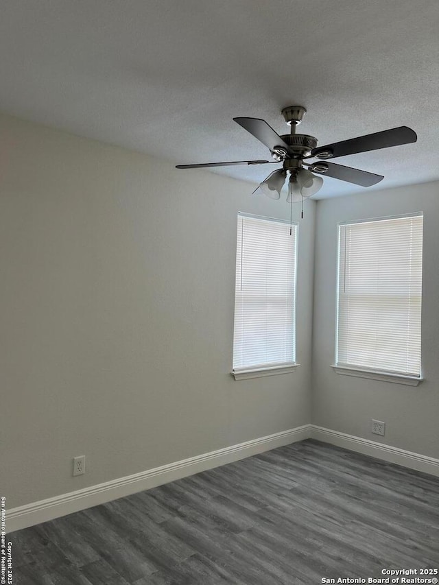 empty room with ceiling fan, a textured ceiling, baseboards, and dark wood-type flooring