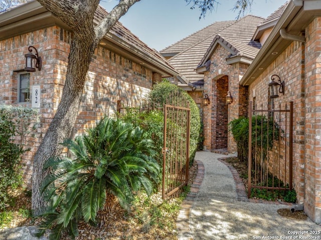 view of property exterior with brick siding and a gate