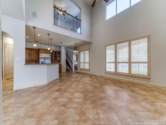 unfurnished living room with stairs, light tile patterned floors, visible vents, baseboards, and ceiling fan with notable chandelier