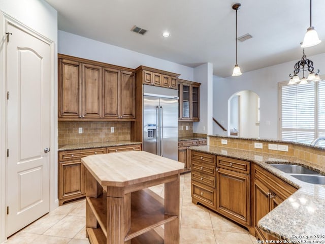 kitchen with built in fridge, open shelves, visible vents, a sink, and wood counters