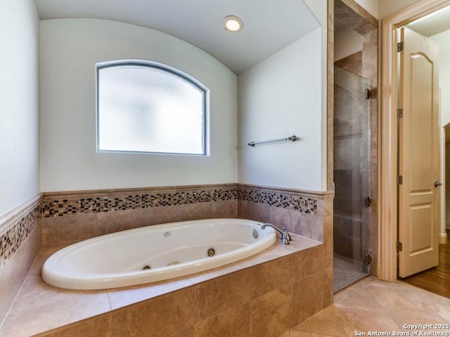 bathroom featuring vaulted ceiling, a jetted tub, tile patterned flooring, and a shower stall