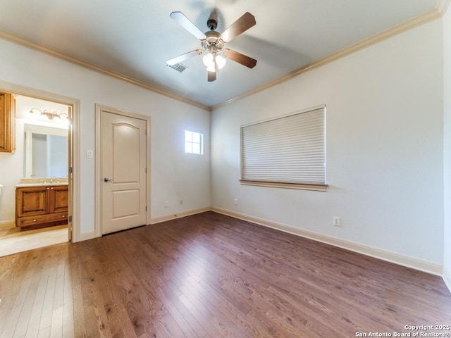 empty room featuring ceiling fan, visible vents, baseboards, light wood-type flooring, and crown molding