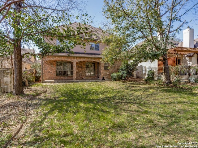 view of front of home with a front lawn, fence, and brick siding