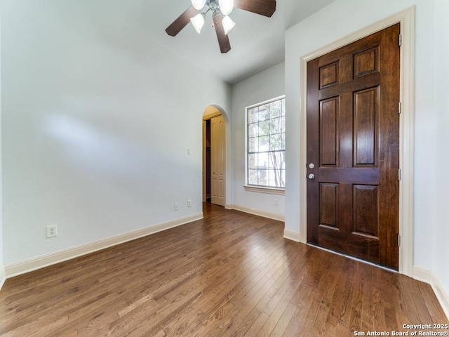 foyer featuring arched walkways, ceiling fan, baseboards, and wood finished floors