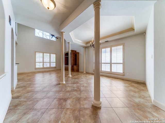 interior space featuring ornate columns, light tile patterned floors, and a raised ceiling