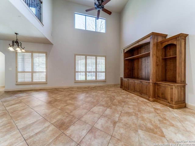 unfurnished living room with light tile patterned flooring, a healthy amount of sunlight, baseboards, and ceiling fan with notable chandelier