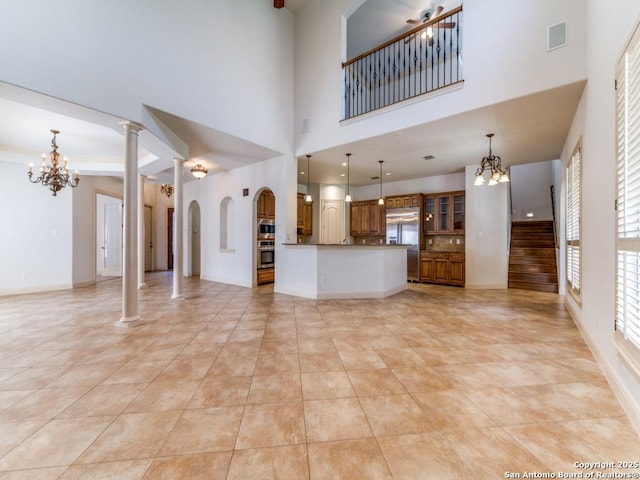 unfurnished living room featuring light tile patterned floors, visible vents, stairway, an inviting chandelier, and ornate columns