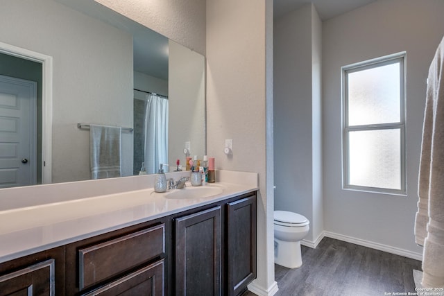 bathroom featuring toilet, baseboards, wood finished floors, and vanity