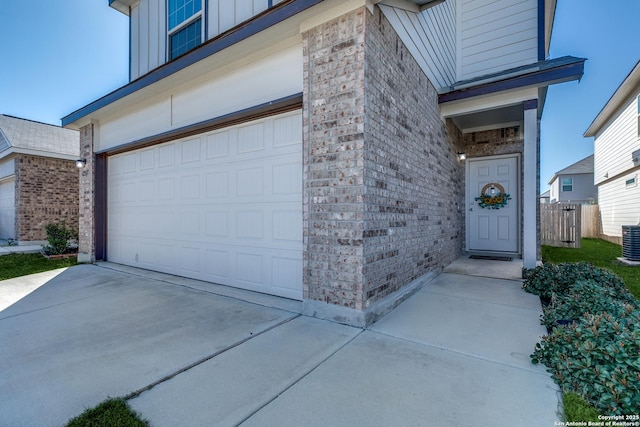 entrance to property with a garage, concrete driveway, board and batten siding, and brick siding