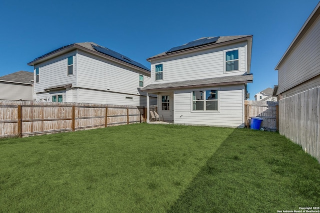 back of property with a yard, solar panels, and a fenced backyard