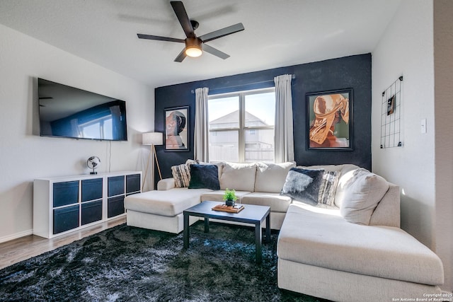 living room with ceiling fan, baseboards, and wood finished floors