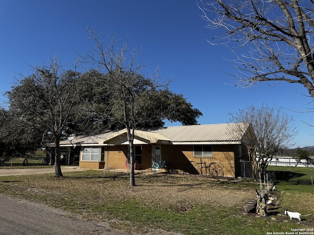 view of front of house featuring driveway, metal roof, a carport, and brick siding