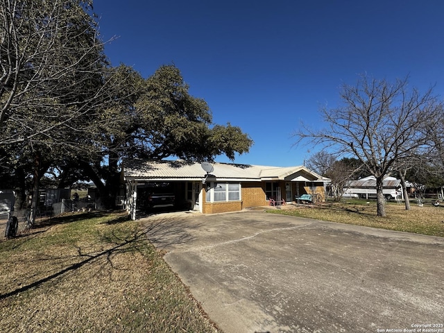 view of front of home with concrete driveway, a front lawn, an attached carport, and brick siding