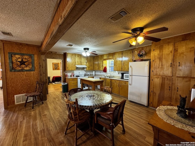 kitchen featuring white appliances, visible vents, brown cabinetry, light countertops, and under cabinet range hood