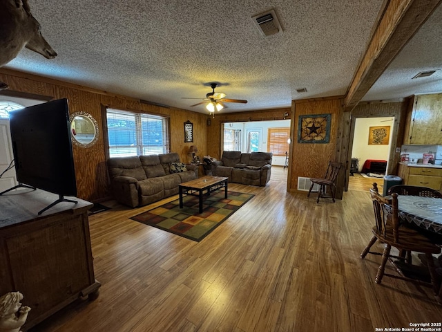 living area with a textured ceiling, wood finished floors, and visible vents