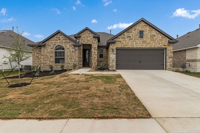 french provincial home with a garage, driveway, central AC, and a front yard