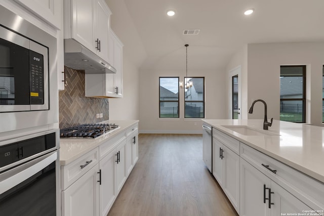 kitchen featuring under cabinet range hood, stainless steel appliances, a sink, visible vents, and light countertops