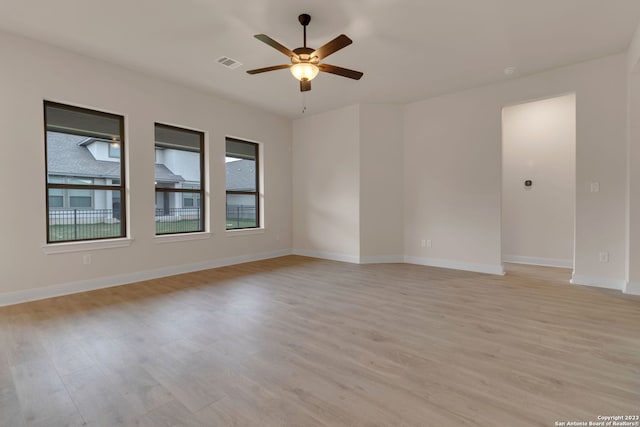 empty room featuring baseboards, a ceiling fan, visible vents, and light wood-style floors