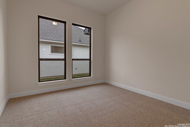 unfurnished room with light colored carpet and baseboards