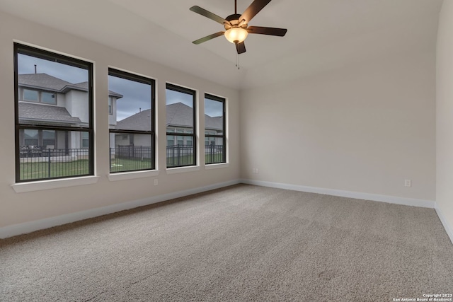 carpeted spare room featuring ceiling fan and baseboards