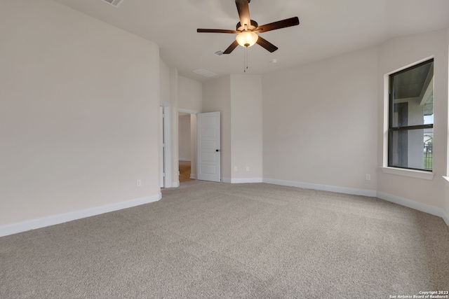 spare room with a ceiling fan, light colored carpet, and baseboards