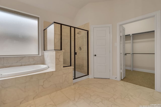 bathroom featuring a garden tub, vaulted ceiling, marble finish floor, a shower stall, and a walk in closet