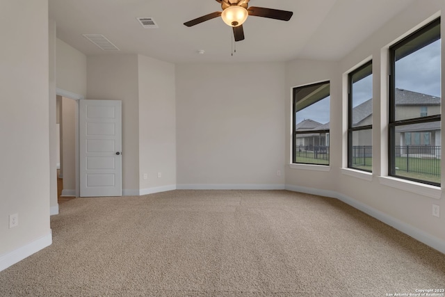 carpeted spare room with ceiling fan, visible vents, and baseboards