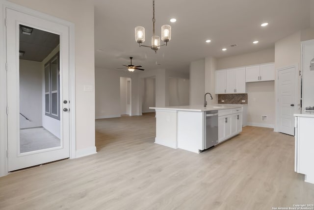 kitchen with decorative light fixtures, light wood-style flooring, backsplash, stainless steel dishwasher, and white cabinetry