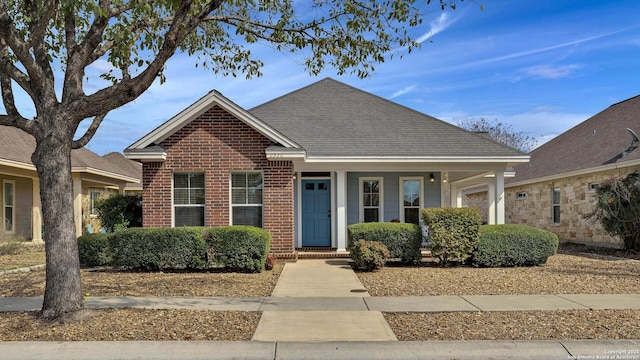 view of front of property with a shingled roof and brick siding