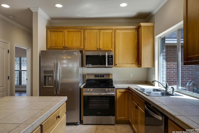 kitchen featuring stainless steel appliances, tile counters, crown molding, and a sink