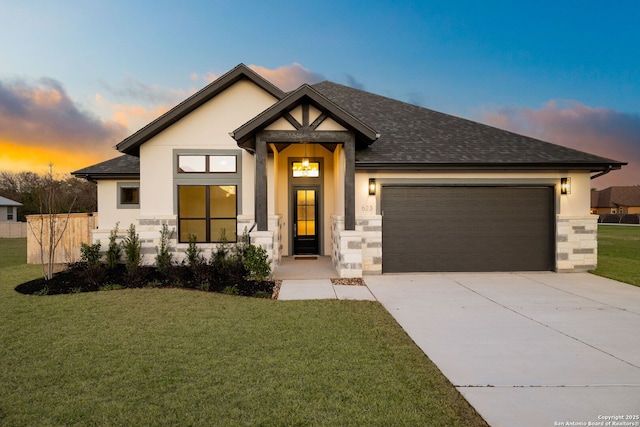 view of front of property with driveway, stone siding, an attached garage, a yard, and stucco siding