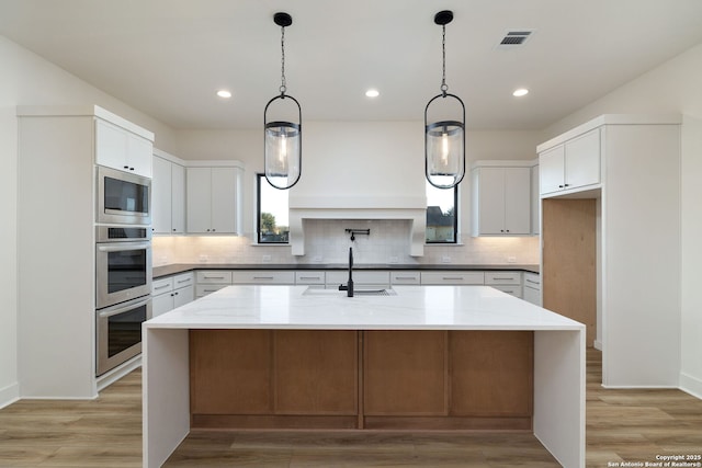 kitchen with stainless steel appliances, visible vents, a sink, and backsplash