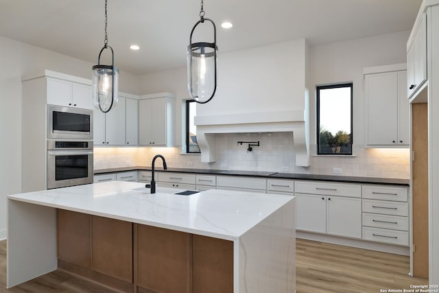 kitchen featuring light wood-type flooring, backsplash, stainless steel appliances, and a sink