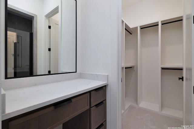 bathroom with a walk in closet and vanity