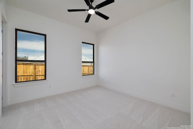 empty room with a healthy amount of sunlight, ceiling fan, baseboards, and carpet flooring