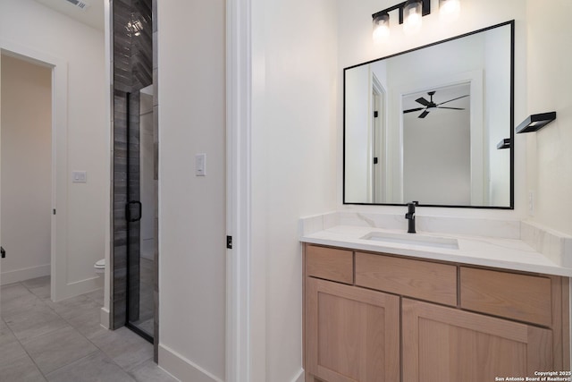 full bathroom featuring toilet, a ceiling fan, a stall shower, vanity, and baseboards