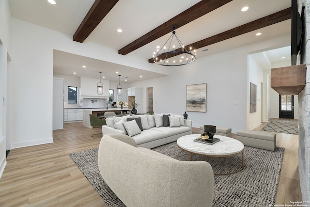 living area with light wood finished floors, recessed lighting, an inviting chandelier, beamed ceiling, and baseboards