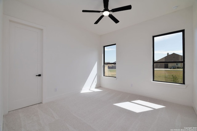 carpeted spare room with a healthy amount of sunlight, ceiling fan, and baseboards