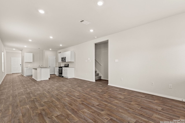 unfurnished living room featuring visible vents, dark wood-type flooring, stairs, a sink, and recessed lighting