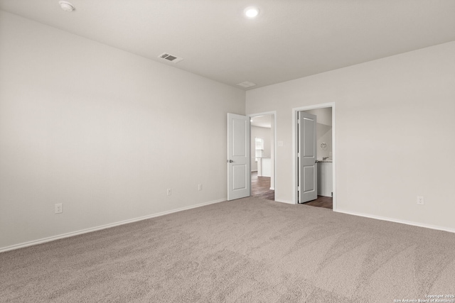 unfurnished bedroom with baseboards, visible vents, connected bathroom, and carpet flooring