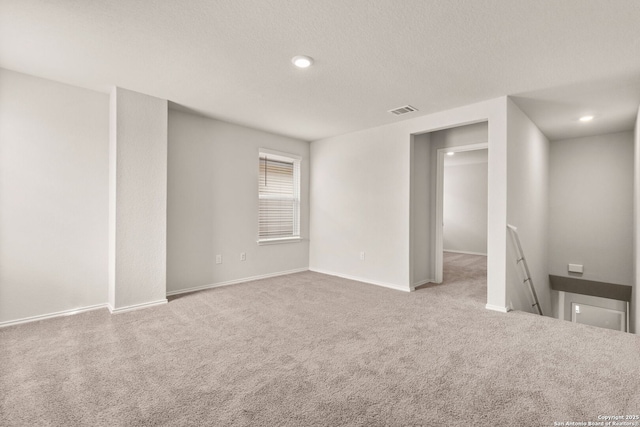 carpeted empty room featuring a textured ceiling, recessed lighting, visible vents, and baseboards